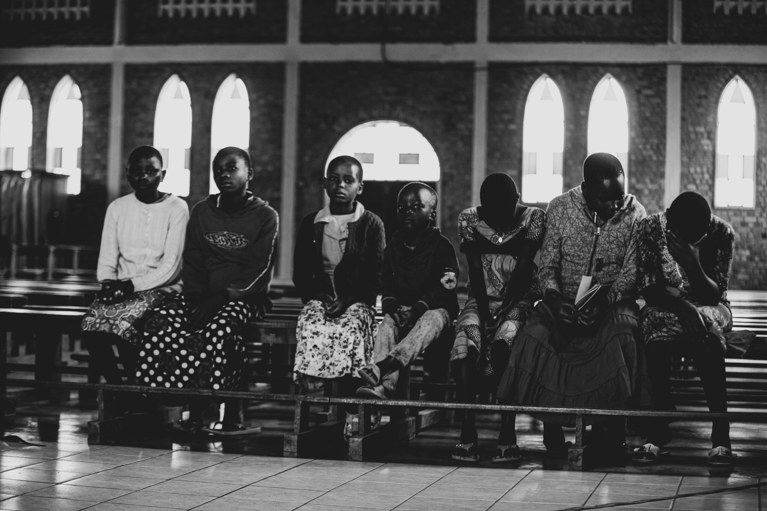 Monochrome image of children sitting quietly in a church setting, displaying a serene and contemplative mood.